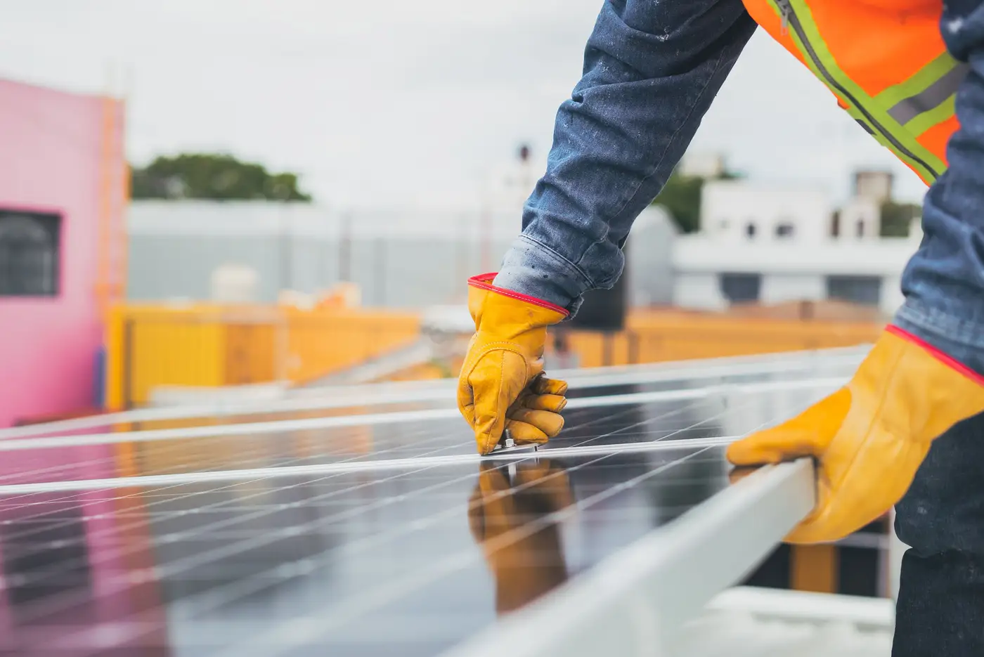 A gloved hand works at the edge of a solar panel during outdoor maintenance.