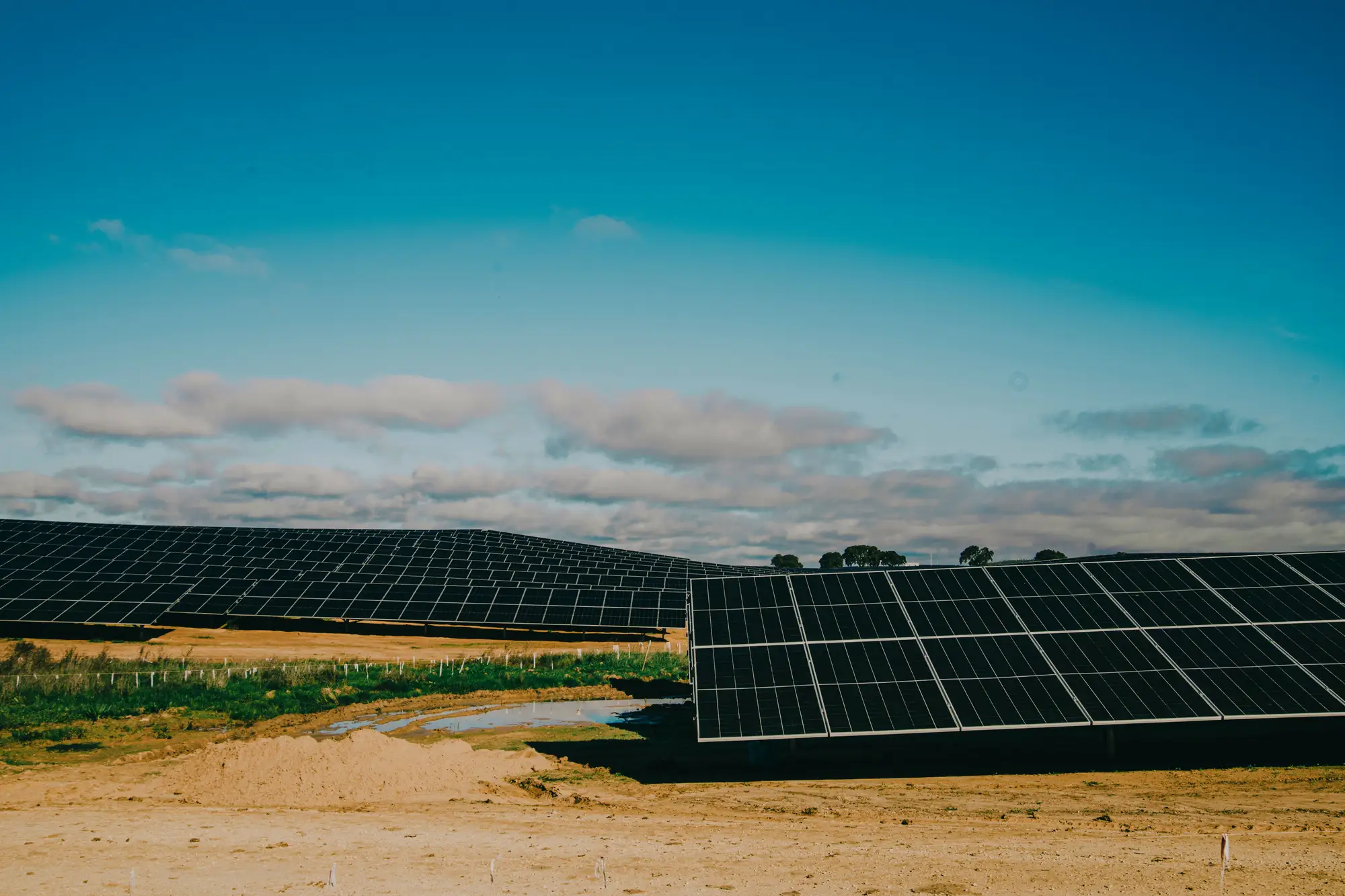 Rows of solar tables on bare, dusty ground under a wide sky